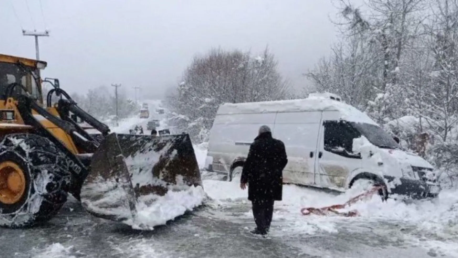 Karlı yolda yan yatan minibüsü iş makinesi ile kurtardılar!