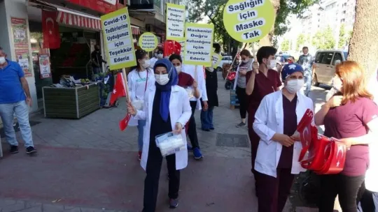 Sağlık çalışanları, maske ve sosyal mesafeye dikkat çekmek için yürüdü