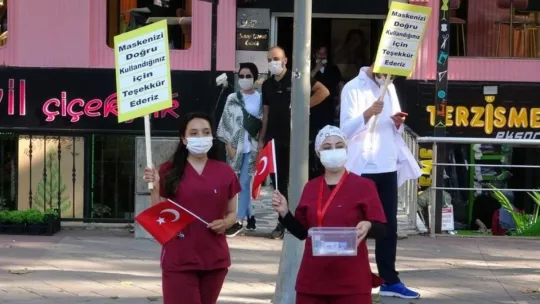 Sağlık çalışanları, maske ve sosyal mesafeye dikkat çekmek için yürüdü