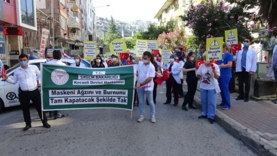 Sağlık çalışanları, maske ve sosyal mesafeye dikkat çekmek için yürüdü